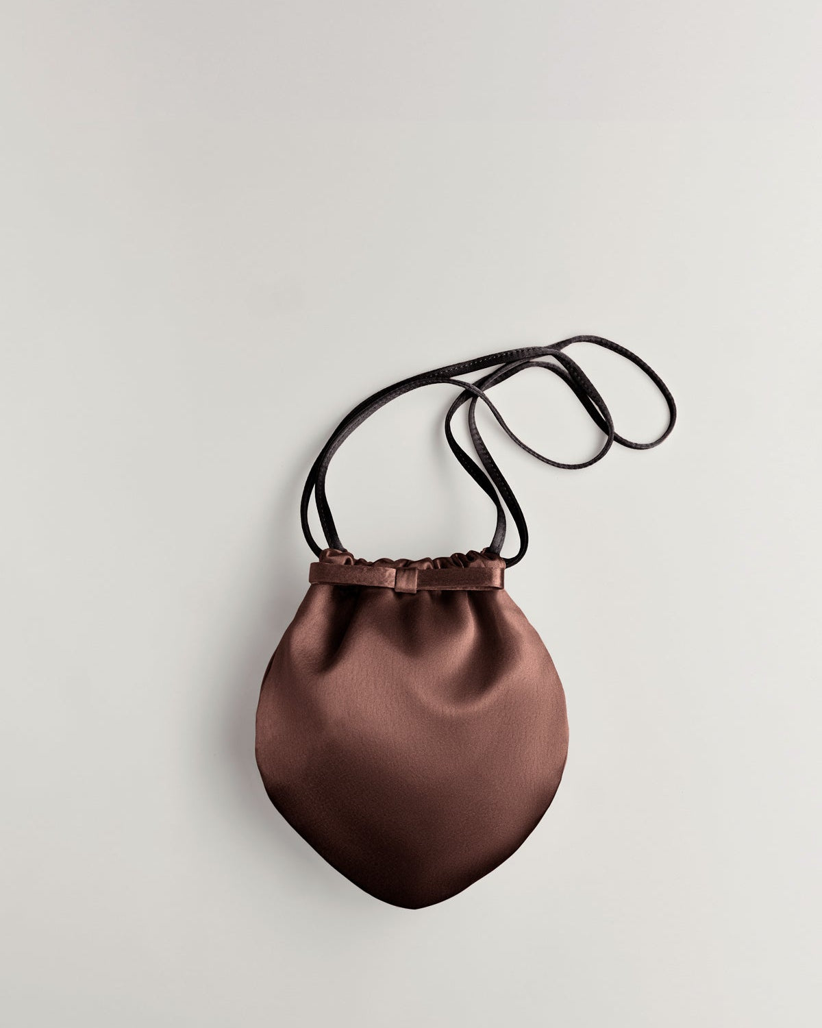 Brown satin drawstring bag with black strap on a light gray background