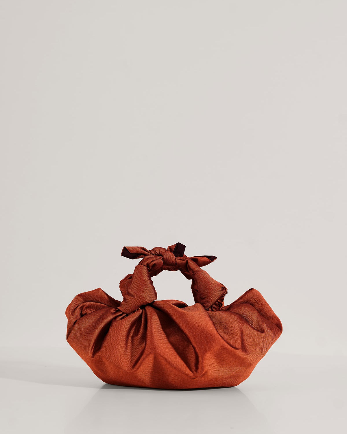 Silk knotted bag with hand-knotted top handles and a clasp closure.