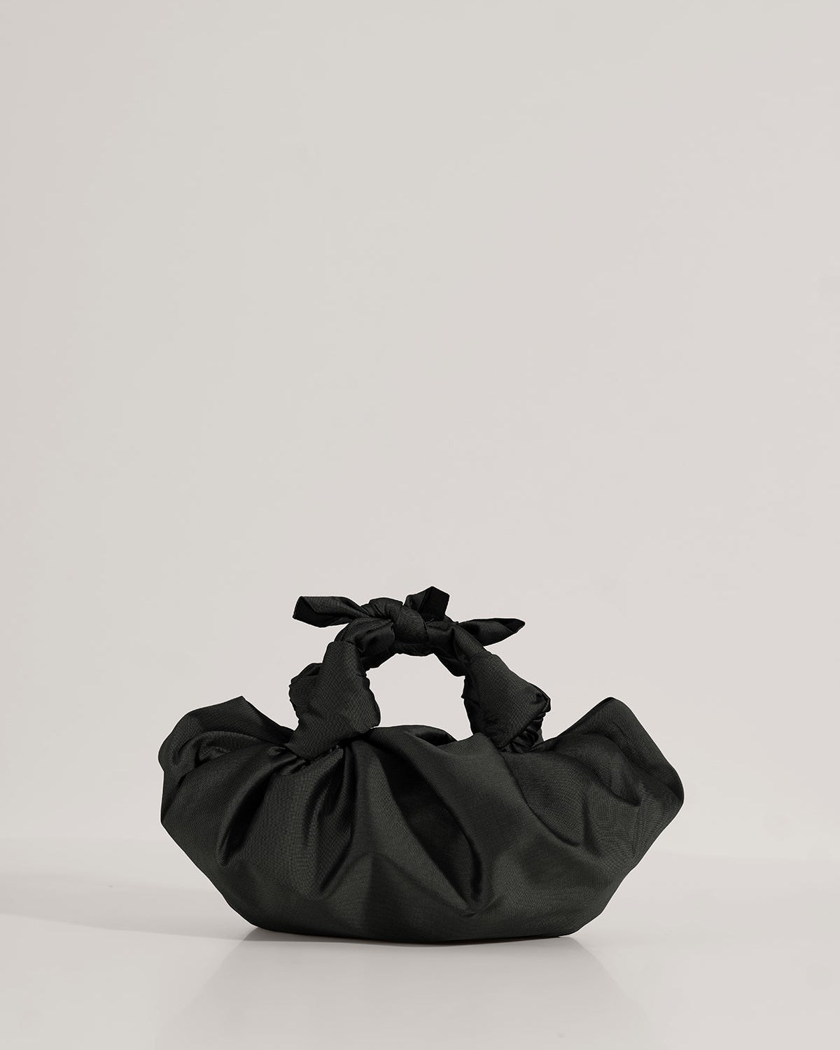 A black silk knotted bag with hand-knotted top handles, displayed against a white background.